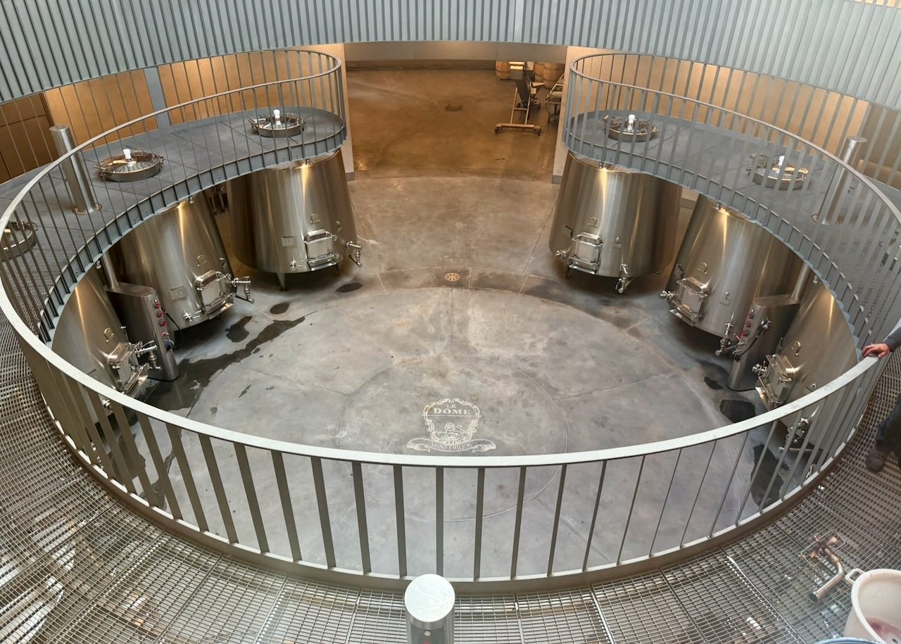 Stainless steel fermentation tanks arranged in a circle around the Le Dôme crest set into the concrete floor, seen from above
