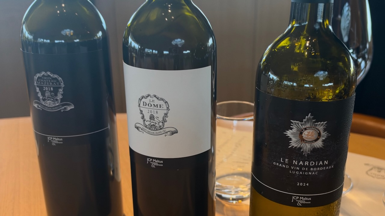 Three bottles on a wooden tasting table: Vieux Château Mazerat 2018, Le Dôme 2018 and Le Nardian 2024